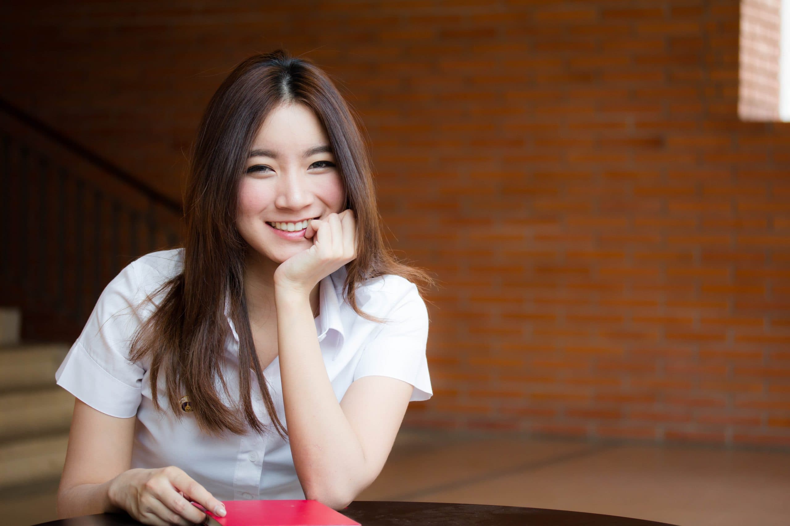 Студентка азиатка улыбающаяся.